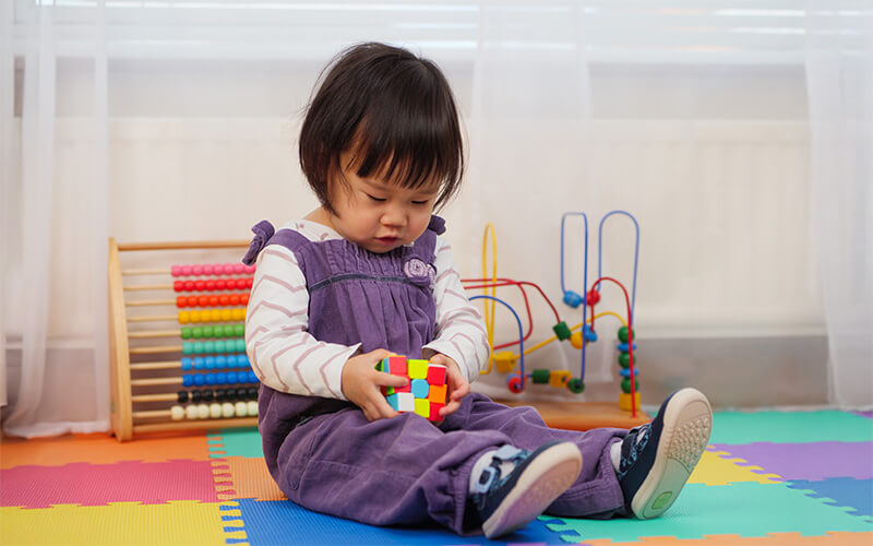 Asian 2 - 3 years old toddler boy child having fun playing colorful cube