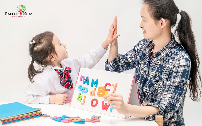 A teacher and preschool girl high-fiving after activity