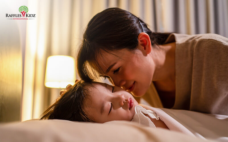 Mother tucking young child into bed for sleep routine.