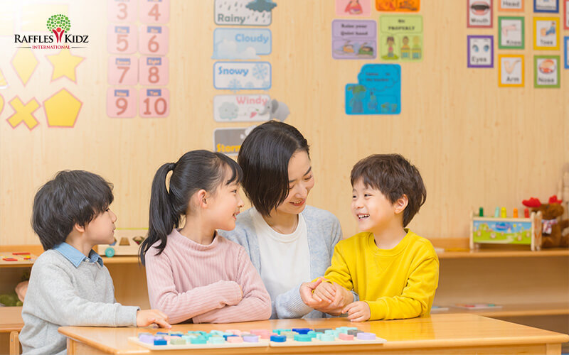 Raffles Kidz teacher chatting with preschool students.