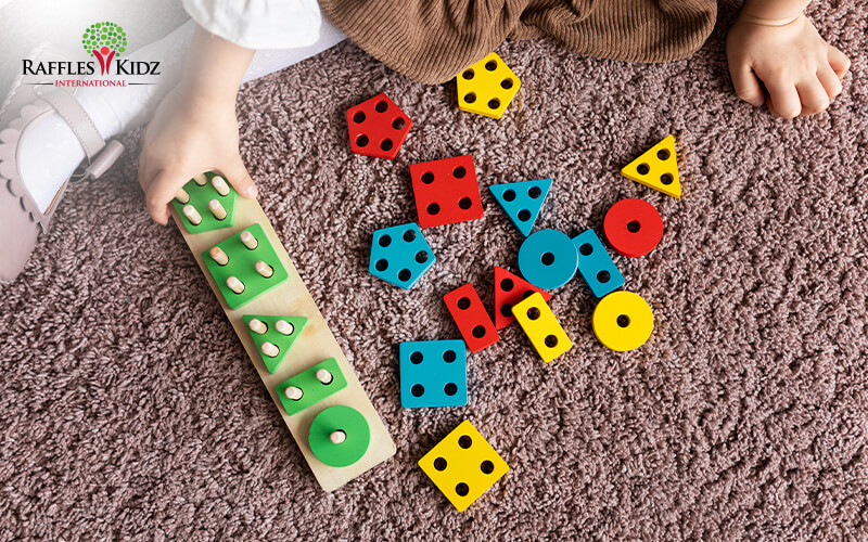 Child playing with colorful Montessori geometric shape sorting board.