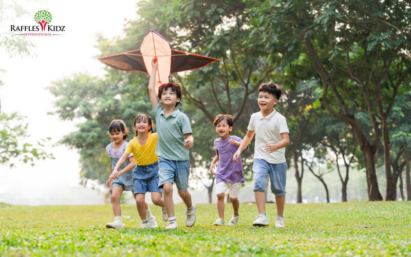 Children running and laughing while flying a kite outdoors.