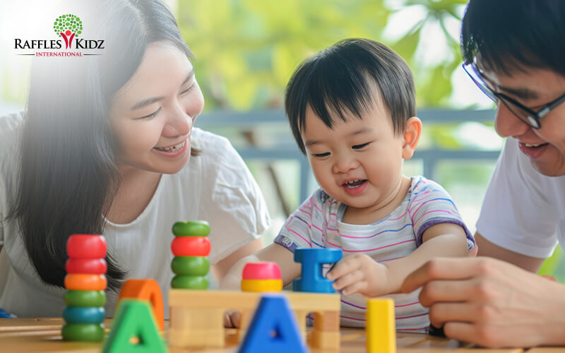 Happy toddler building colorful block tower with supportive parents.