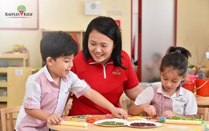 Teacher supporting preschool children during creative activity in class.