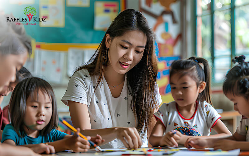 Asian Teacher helping young children with a drawing activity at a classroom table