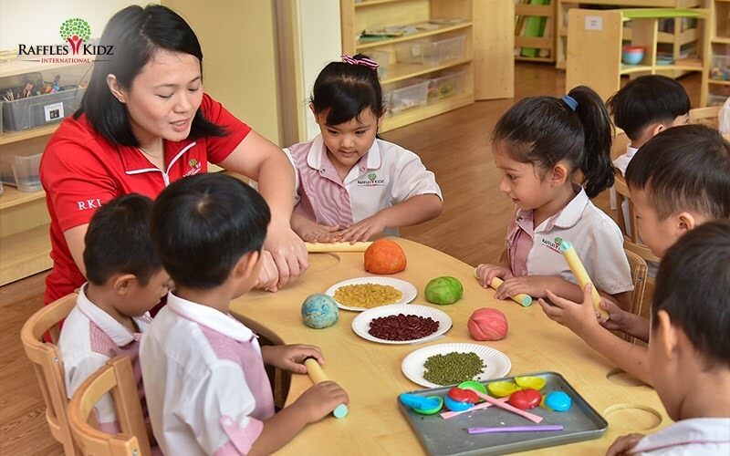 A Raffles Kidz teacher engaging with students during a creative enrichment programme.