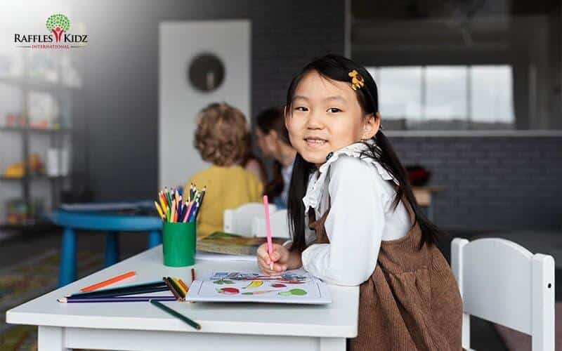 A young girl smiling while participating in enrichment programmes at Raffles Kidz preschool.