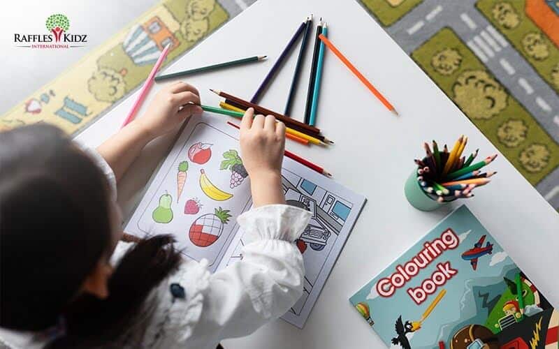 Close-up of a child using colorful pencils during an enrichment programme to complement preschool learning.