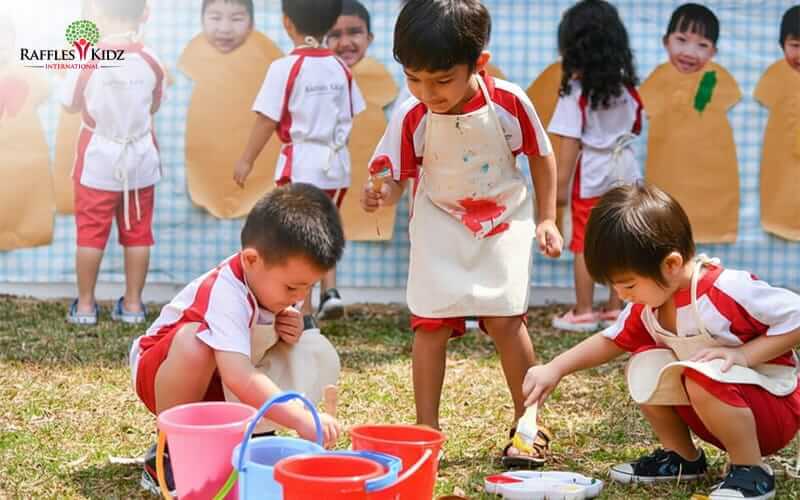 Preschoolers engaging in outdoor sensory painting at Raffles Kidz