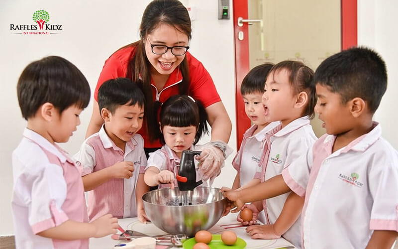 Raffles Kidz teacher guiding students during a baking activity